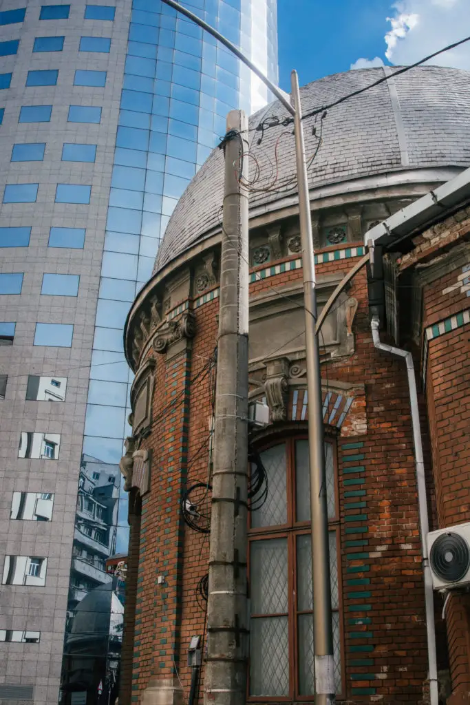 historic brick building in front of modern glass office in bucharest