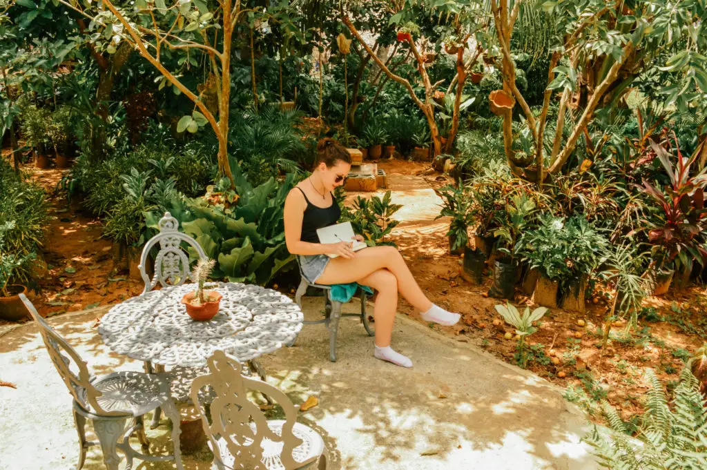 girl sat in jungle garden writing in a diary