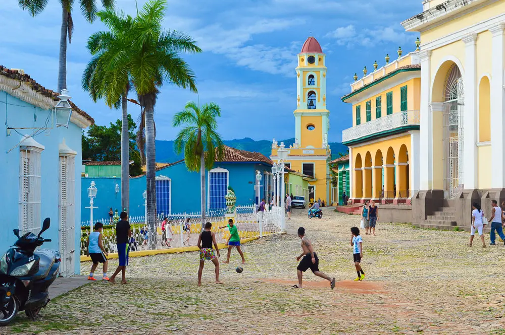 kids playing football on cobbles in front of brightly painted buildings