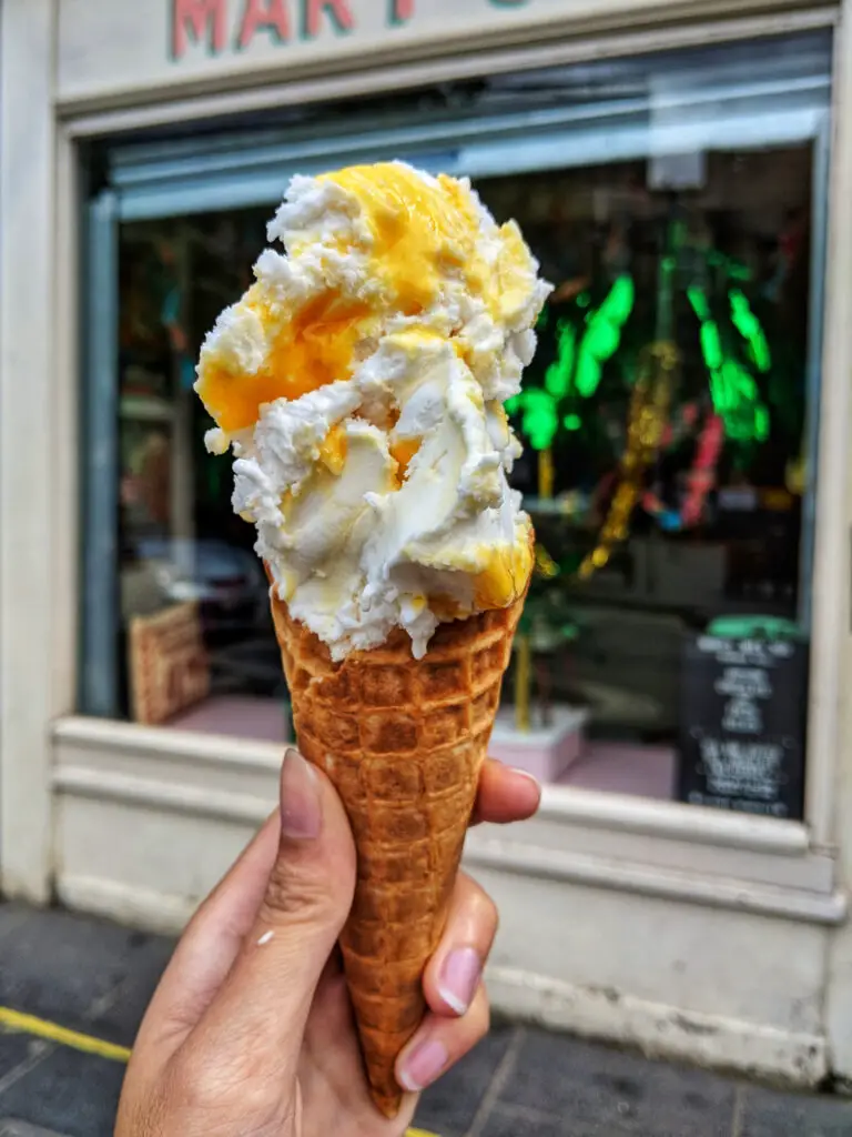hand holding icecream in front of shop